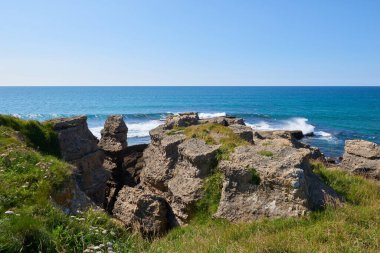 Bitkilerle çevrili vurucu uçurumlar ve turkuaz mavi bir deniz..