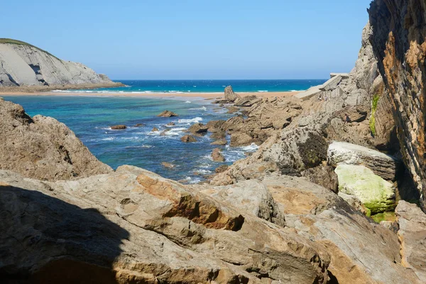 Güzel mavi gökyüzü olan sakin bir denizin yanındaki sarp kayalıklar