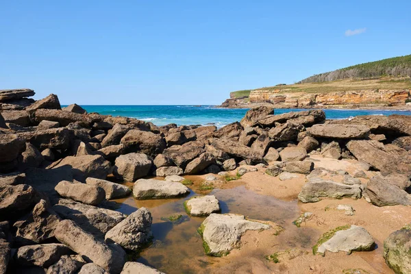 Derin mavi denizi ve berrak mavi gökyüzü olan sarp kayalıklar.