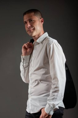 Siyah ceketli genç bir adam stüdyoda poz veriyor..