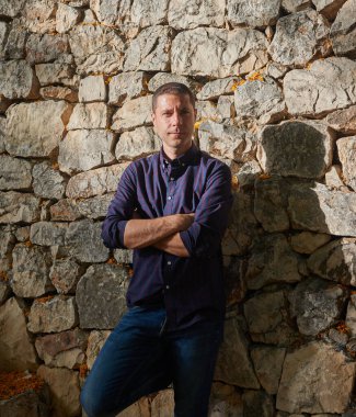 Taş duvarda poz veren çekici genç bir adam..