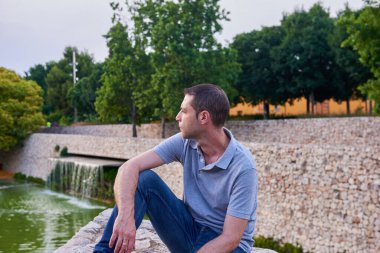 Parktaki duvarda oturan genç bir manken.