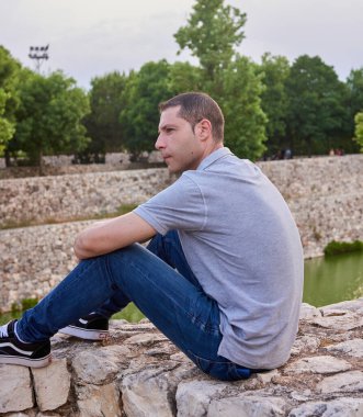 A young model seated on a wall in a park