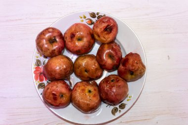 Büyük beyaz bir tabakta sekiz adet pişmiş elma var..