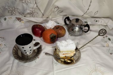 Yukarıdan bak. Masanın üzerinde bir fincan kahve, tatlı spatulasında bir fincan kek, meyve ve şeker kasesi var..