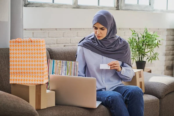 若いアラビア人の女性はクレジットカードを使用してオンラインショップで何かを購入しようとしている ストックフォト