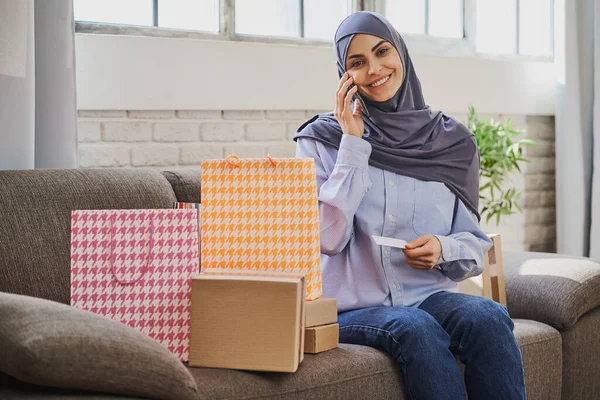 Pretty Arabian woman holding a credit card and talking on the phone Stock Picture