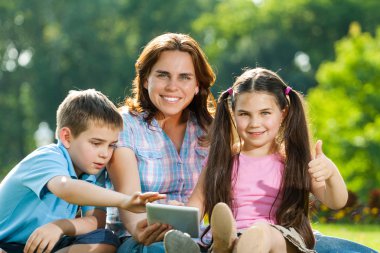 mutlu bir aile çim üzerinde yalan dizüstü kullanarak