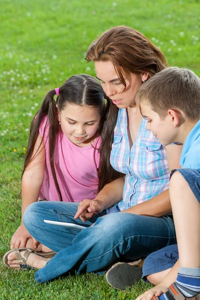 Lycklig familj använder laptop liggande på gräs — Stockfoto