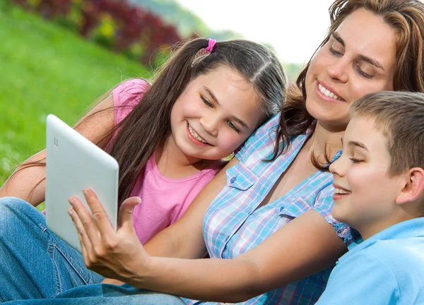 Lycklig familj använder laptop liggande på gräs — Stockfoto