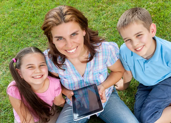 幸福的家庭使用的便携式计算机放在草地上 — 图库照片
