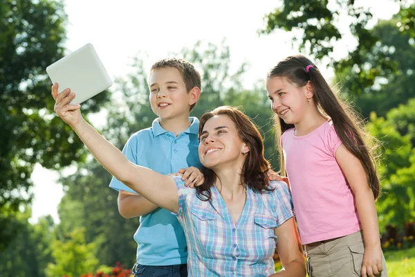 Familia feliz usando el ordenador portátil acostado en la hierba — Foto de Stock