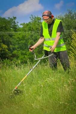 Çim biçme makinesiyle çim biçen işçiler