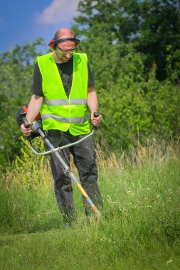Çim biçme makinesiyle çim biçen işçiler