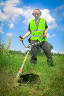 Çim biçme makinesiyle çim biçen işçiler