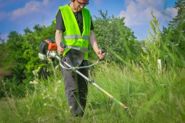 Çim biçme makinesiyle çim biçen işçiler