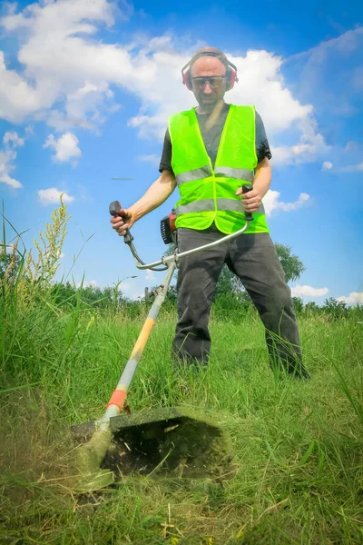 Çim biçme makinesiyle çim biçen işçiler
