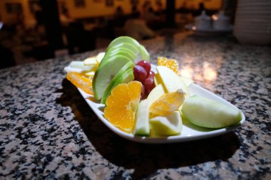 Taze sebze ve yenilebilir çiçek. Sağlıklı çiğ meyve çeşitleri. Beyaz tabakta, kapalı masada, seçici bir odak noktası olan çiğ meyve çileği tabağı..