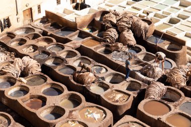 FEZ, MOROCCO - 31 Ekim 2021: İnsanlar Fez City 'de ziyaret etmek için en popüler yerlerden biri olan Chouara Tannery' de deri boyuyorlar