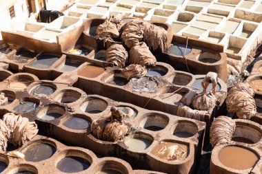 FEZ, MOROCCO - 31 Ekim 2021: İnsanlar Fez City 'de ziyaret etmek için en popüler yerlerden biri olan Chouara Tannery' de deri boyuyorlar
