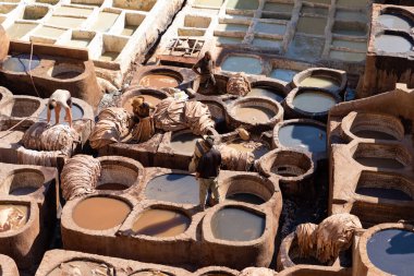 FEZ, MOROCCO - 31 Ekim 2021: İnsanlar Fez City 'de ziyaret etmek için en popüler yerlerden biri olan Chouara Tannery' de deri boyuyorlar
