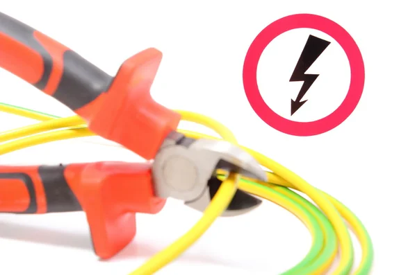 Alicates de metal, cable verde-amarillo y señal de peligro de alto voltaje —  Fotos de Stock