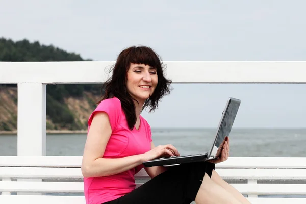 Woman sitting on the bench with her laptop