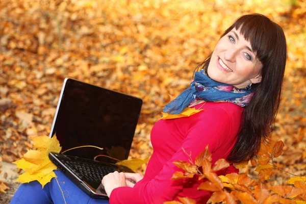 Vrouw met laptop in herfst park — Stockfoto