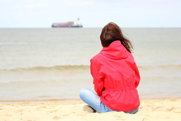 Woman sitting on the beach and looks at sea, summer time — Stock Photo, Image