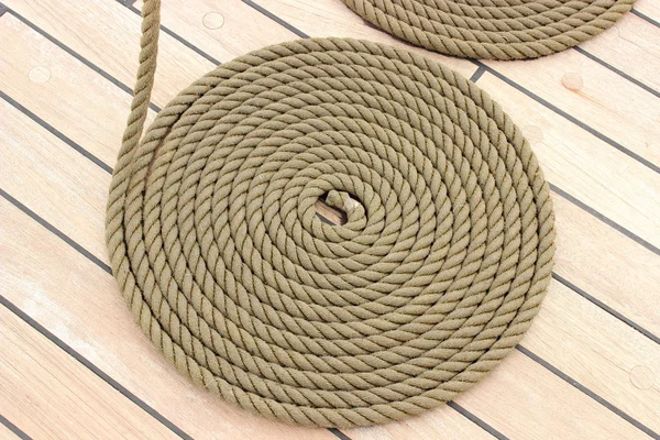 Thick rope wrapped in spiral lying on deck of ship — Stock Photo, Image