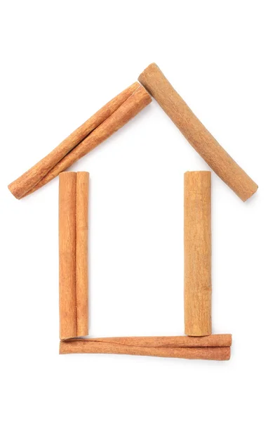 Cinnamon sticks and shape of house. White background — Stock Photo, Image