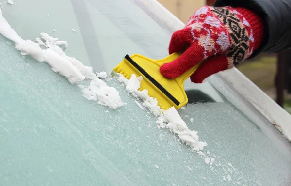 刮冰从汽车挡风玻璃上的女人的手 — 图库照片