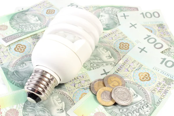Bílé úsporná žárovka ležící na hromadu papírových peněz — Stock fotografie