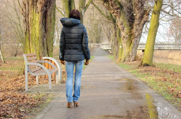 Lonely woman walking in park on cold rainy day — Stock Photo, Image