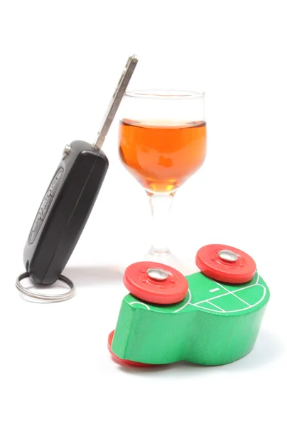 Overturned model vehicle, glass of wine and car key. White background — Stock Photo, Image