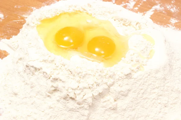 Broken egg in heap of flour lying on table — Stock Photo, Image