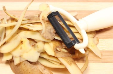 Patates soyma ahşap kesme tahtası üzerinde yalan ile peeling