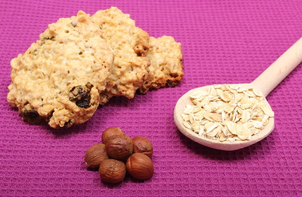 Oatmeal cookies with flakes and hazelnut on purple background — Stock Photo, Image