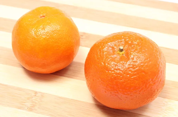 Mandarinas frescas e laranja sobre fundo de madeira — Fotografia de Stock