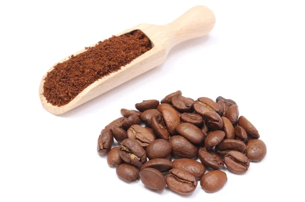 Ground coffee on wooden spoon and heap of grains — Stock Photo, Image