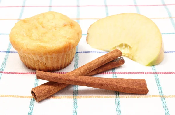 Baked muffin, fresh apple and cinnamon sticks on colorful cloth — Stock Photo, Image
