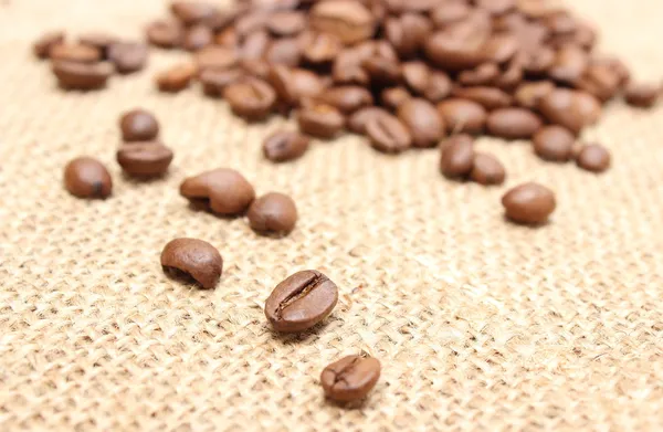 Кофейные зёрна на джутовом фоне — стоковое фото