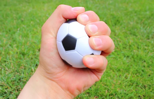 Çim zemin üzerine adamın elini küçük stres topu — Stok fotoğraf