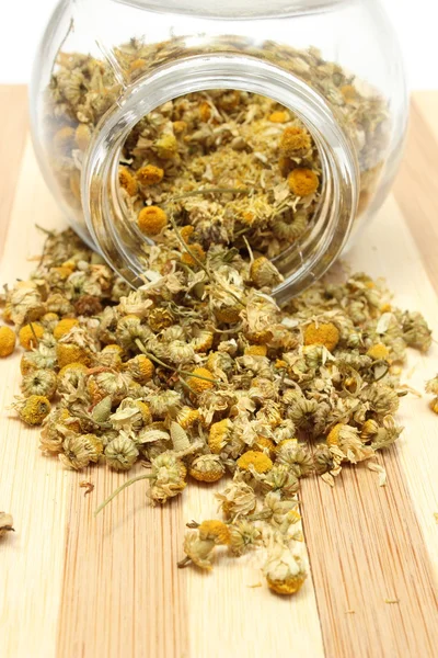 Heap of dried chamomile in glass jar — Stock Photo, Image