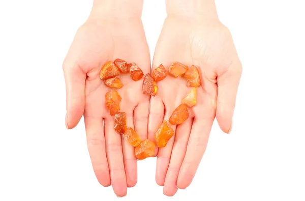 Raw amber shaped heart on hand of woman — Stock Photo, Image