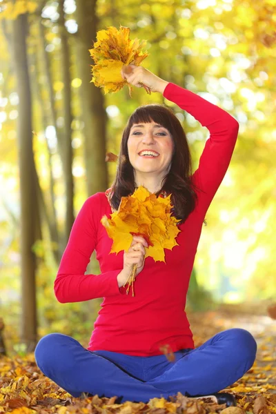 Mujer en el parque de otoño con hojas en la mano — Foto de Stock