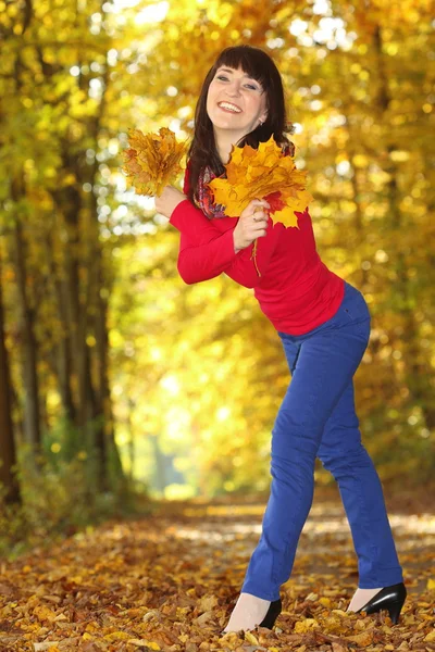 Улыбающаяся женщина с кленовыми листьями в руке — стоковое фото