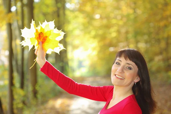 Smiling woman with maple leaves in hand — Stock Photo, Image