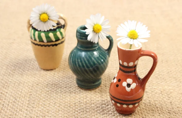 Margaritas blancas en jarrones decorativos de cerámica sobre lienzo de yute — Foto de Stock