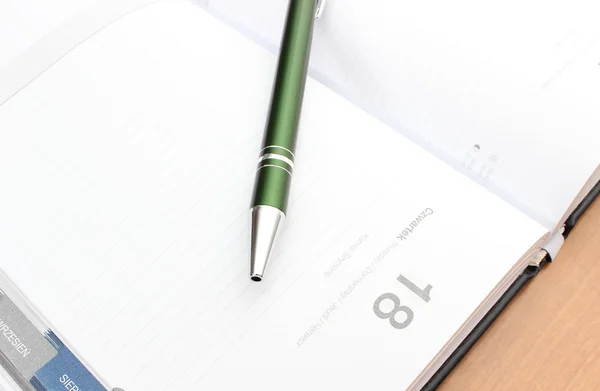 Closeup πράσινο στυλό πάνω σε διοργανωτής σημειωματάριο — Φωτογραφία Αρχείου
